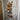 Wall-mounted steampunk wine rack made from copper pipes holding four bottles against rustic wood paneling