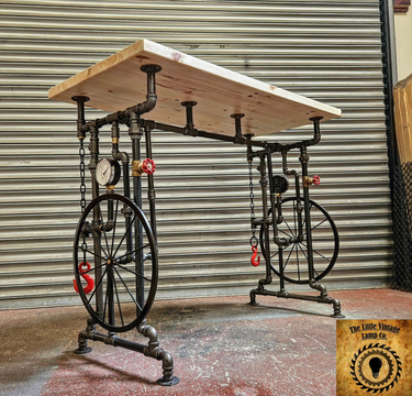 Handmade steampunk industrial table with pipe legs, wheels, chains, and a wood top
