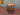 Industrial side table with solid wood shelves and metal pipe legs on a red floor
