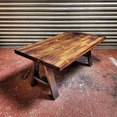 A-frame industrial steampunk coffee table with a dark wood top and metal legs on a red floor.