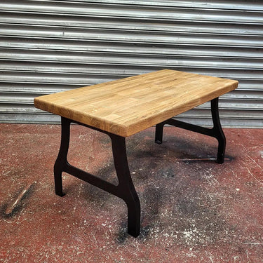 Industrial steampunk coffee table with solid wood top and black metal legs on workshop floor