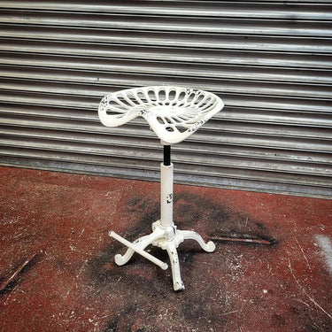 White steampunk industrial bar stool with tractor seat and cast iron base on red floor