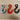 Three industrial metal lifting hooks in silver, red, and black on a wooden surface
