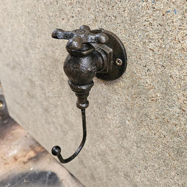 Industrial steampunk cast iron hook mounted on a textured wall