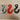 Three industrial metal hooks in silver, red, and black on a wooden surface
