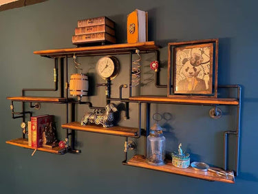 Industrial steampunk wall shelf with wooden planks, pipes, books, decor and vintage art.
