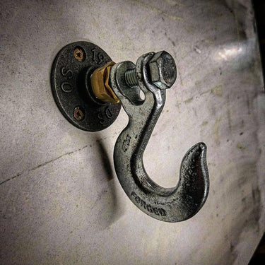 Industrial metal coat hook with exposed bolts mounted on a concrete wall