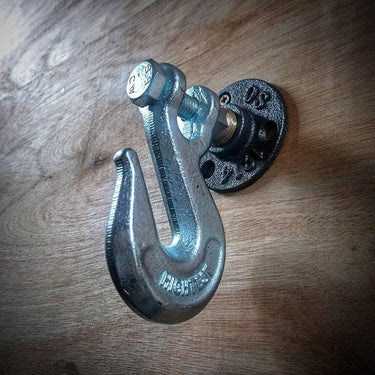 Industrial metal coat hook with pipe flange mount on wooden surface, steampunk home decor