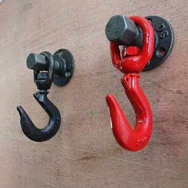 Industrial-style coat hooks with black and red metal hooks mounted on wood wall