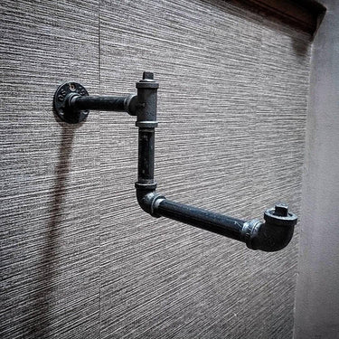 Industrial black iron pipe clothes hanger rail mounted on textured wall