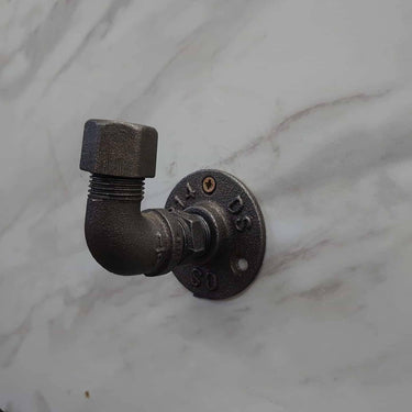 Industrial rustic coat hook made from black metal pipe on a marble wall