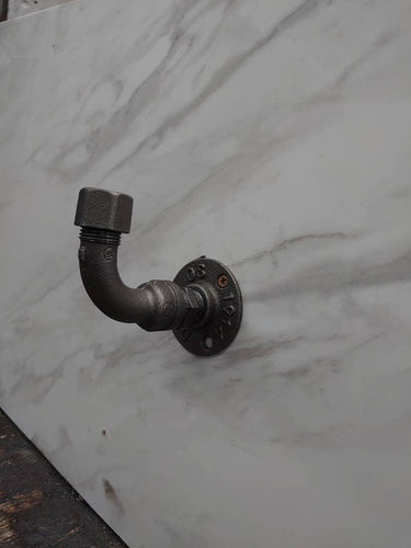Industrial rustic coat hook made from metal pipe on marble-effect wall