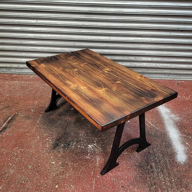 Industrial steampunk coffee table with dark wood top and black metal legs on concrete floor
