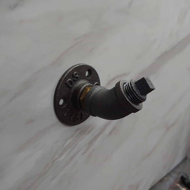 Retro industrial coat hook made from metal pipe, mounted on a marble wall