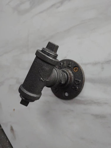 retro industrial iron coat hook with pipe fitting design mounted on a marble wall