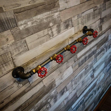 Retro industrial coat rack with red valve hooks on rustic wood wall