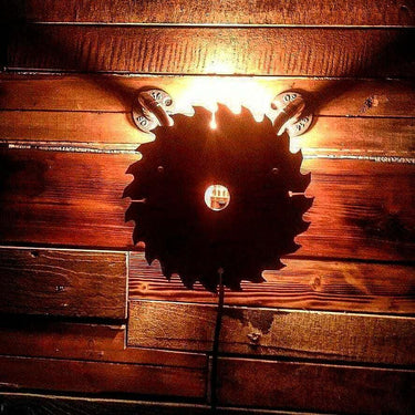 Rustic saw blade wall light with exposed bulb and industrial pipe fittings on wooden wall