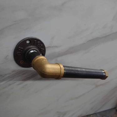 Industrial steampunk pipe toilet paper holder in brass and black metal on marble wall