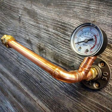 Steampunk copper pipe toilet paper holder with pressure gauge on rustic wood wall