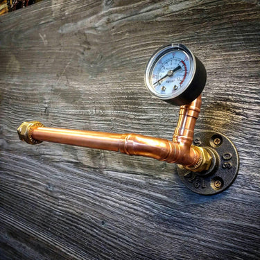 Steampunk copper pipe toilet paper holder with pressure gauge on rustic wood wall