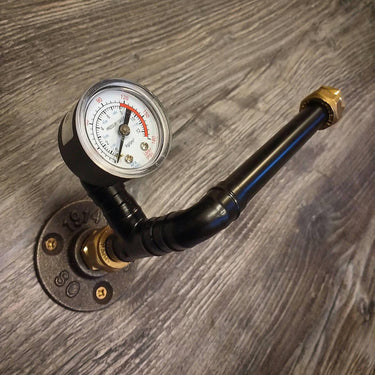 Steampunk black pipe toilet paper holder with pressure gauge on wood wall