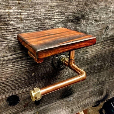 Steampunk copper pipe toilet paper holder with wooden shelf on rustic wood wall