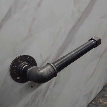 Industrial steampunk pipe toilet paper holder mounted on a marble wall