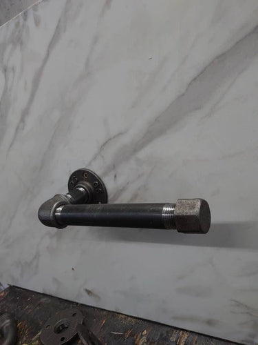 Industrial steampunk pipe toilet paper holder mounted on marble wall