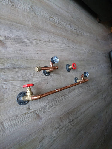 Steampunk pipe toilet set with copper pipes, red valve handles, and pressure gauges on wood floor