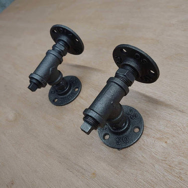 Pair of steampunk industrial pipe wall brackets on a wooden surface