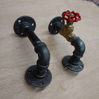 Pair of industrial steampunk pipe wall brackets with red valve handle on light wood surface