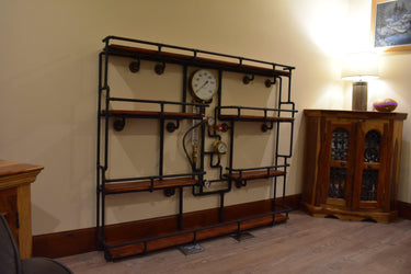 Industrial steampunk shelving unit with black pipe frame, wood shelves, and vintage gauges