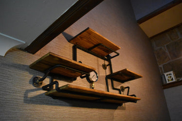 Steampunk shelving unit with wood shelves and black iron pipe fittings on wall