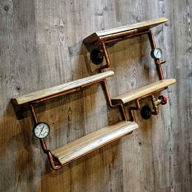 Steampunk industrial shelving unit with copper pipes, wood shelves, and gauge accents on wood wall.