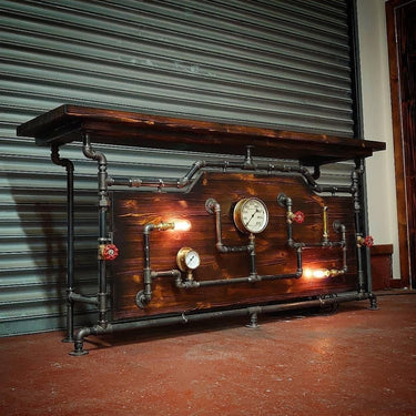 Steampunk bar table with wood top, exposed metal pipes, vintage gauges, and industrial lighting.