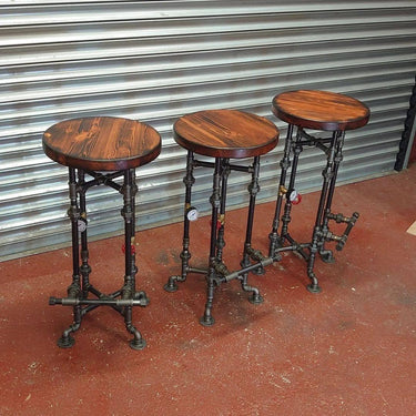 Set of three steampunk industrial bar stools with wooden seats and metal pipe bases
