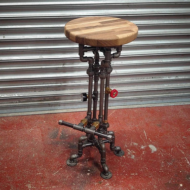Steampunk bar stool with wooden seat and metal pipe base featuring industrial fittings.