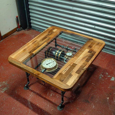 Steampunk coffee table with glass top, exposed vintage gauges, wood frame, and metal pipe legs