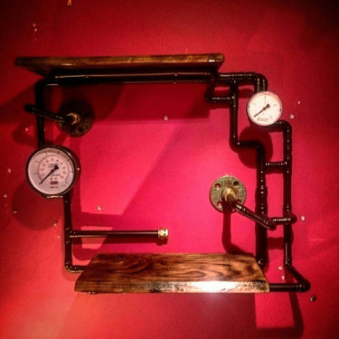 Steampunk shelving unit with dark wood shelves, metal pipes, and vintage pressure gauges on red wall