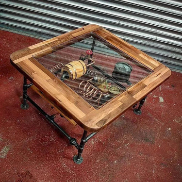 Steampunk coffee table with glass top, wood frame, and exposed industrial metal gears