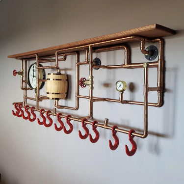 Steampunk coat rack with copper pipes, red hooks, pressure gauges, and a wood shelf