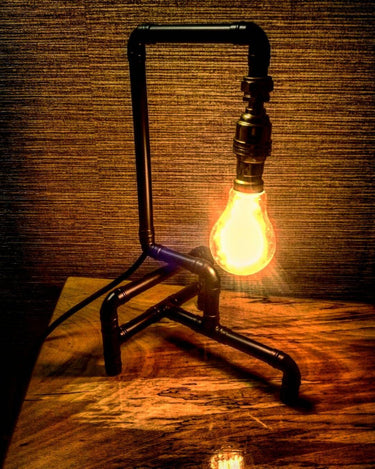 Industrial pipe style table lamp with exposed vintage bulb on wooden surface