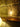 Industrial pipe style table lamp with exposed bulb on wooden shelf against stone wall