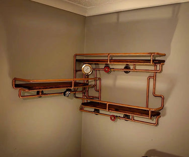 Steampunk industrial shelving unit with copper pipes, wood shelves, and vintage gauges on a wall.