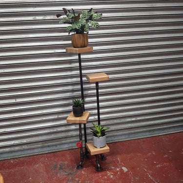 Industrial steampunk plant stand with wooden shelves and metal pipes, holding potted plants
