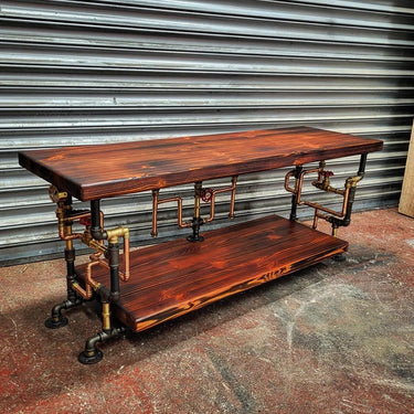 Handmade steampunk coffee table with industrial pipe legs and dark wood shelves