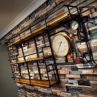 Steampunk industrial shelving unit with wood shelves, exposed pipes, and large pressure gauge on a rustic wall.