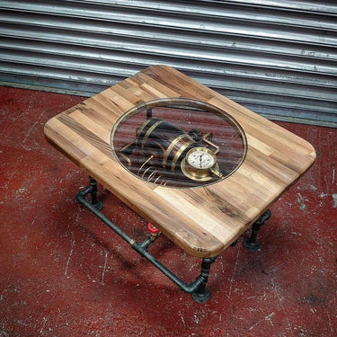 Steampunk coffee table with exposed gears and pressure gauge under glass, industrial pipe legs