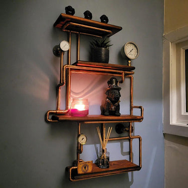 Steampunk shelving unit with copper pipes, pressure gauges, and industrial decor on a wall.