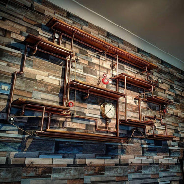 Industrial steampunk wall shelving unit with copper pipes, wooden shelves, and vintage clock.